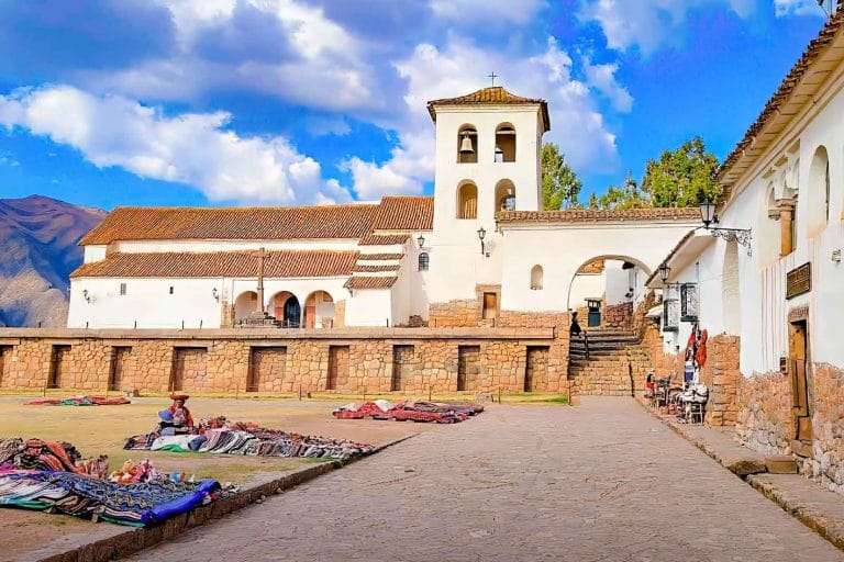 Vista del Monasterio y la Iglesia colonial de Chinchero, con artesanas vendiendo coloridos textiles en la explanada de la plaza inca.