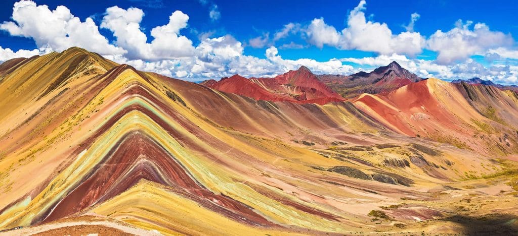 Panorama completo de la Montaña de Siete Colores (Vinicunca), mostrando las vibrantes franjas de colores minerales que caracterizan este atractivo natural andino en Cusco.